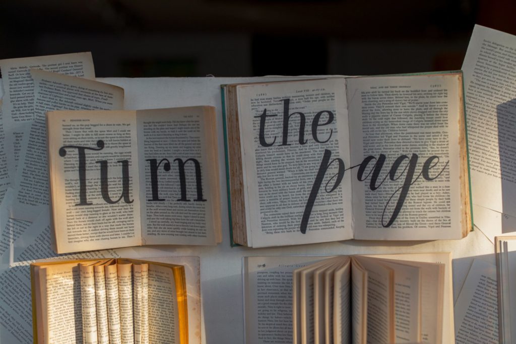 Image of two open books with marker writing added to say "Turn the page."